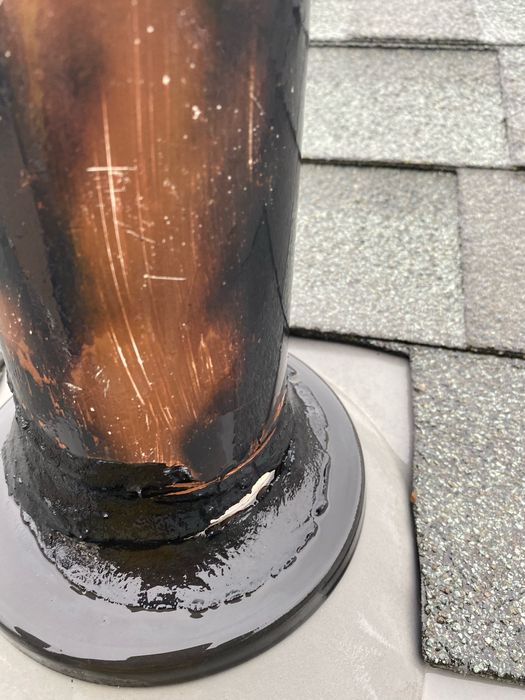 What we found before repair: tight close-up of a copper vent pipe collar at a pipe boot, where black sealant has cracked and separated from the pipe and a light-colored gap shows through.